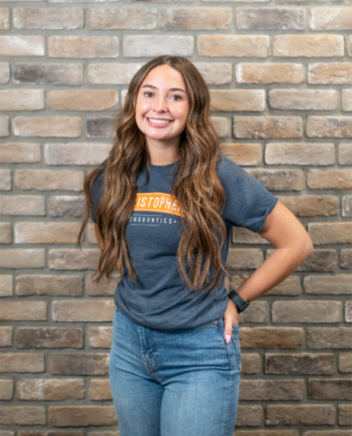 Justice, a Christopher Orthodontics team member, smiling in a Christopher Orthodontics t-shirt